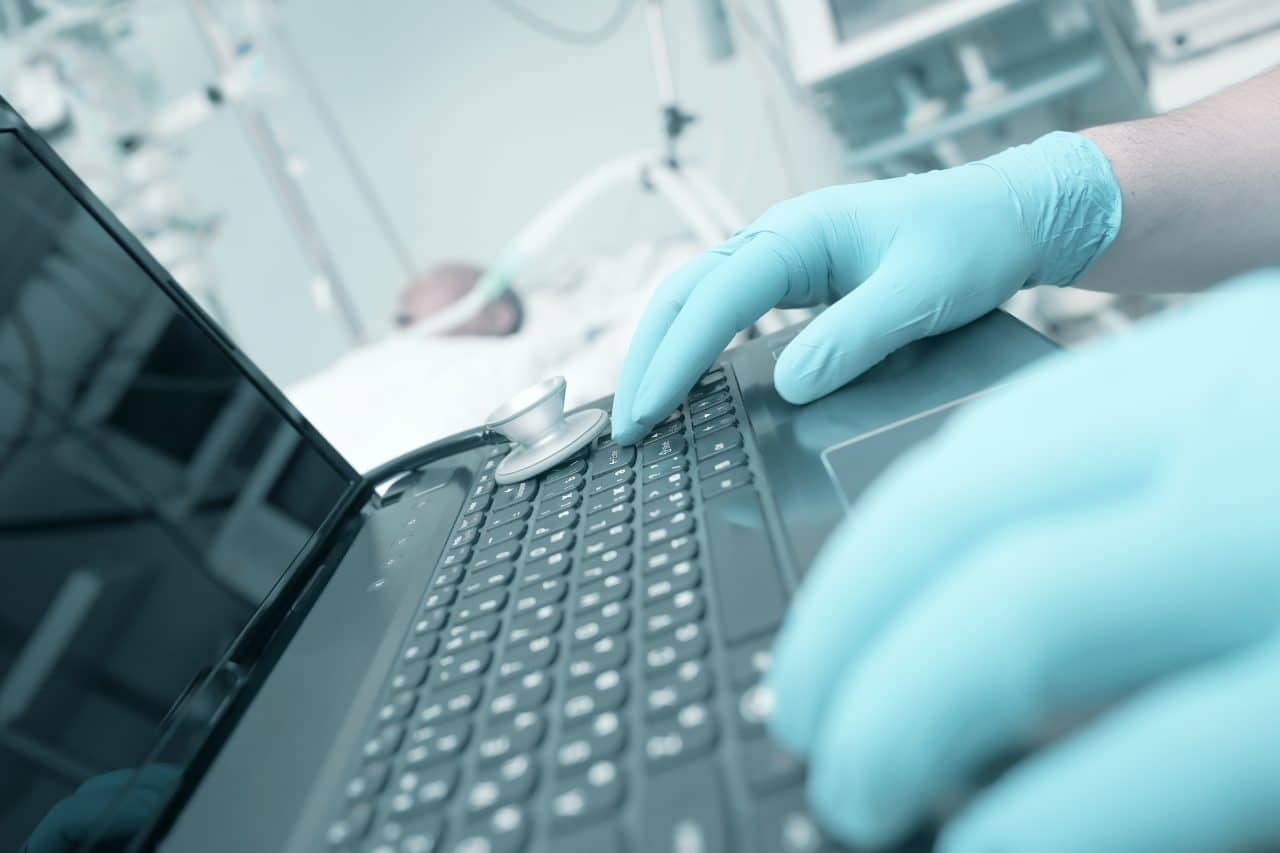 Doctor typing on laptop in the intensive care