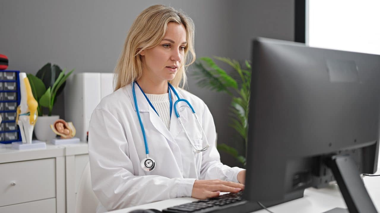 Young blonde woman doctor using computer working at clinic