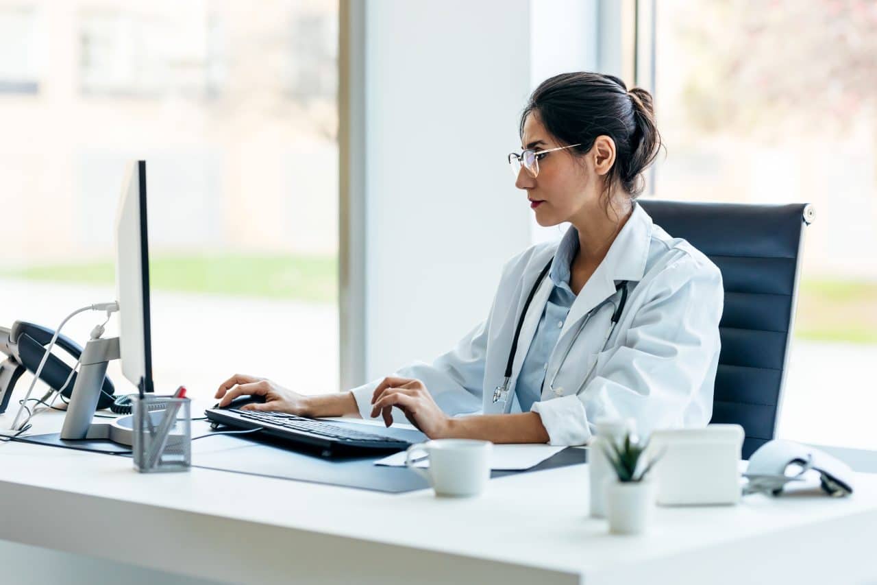 Beautiful female doctor working with computer in medical consult