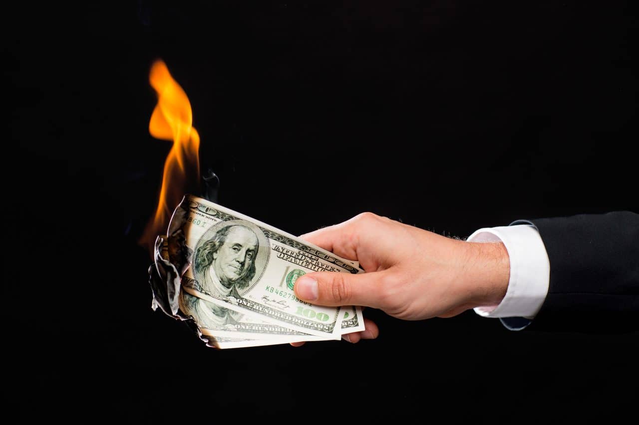 close up of male hand holding burning dollar money