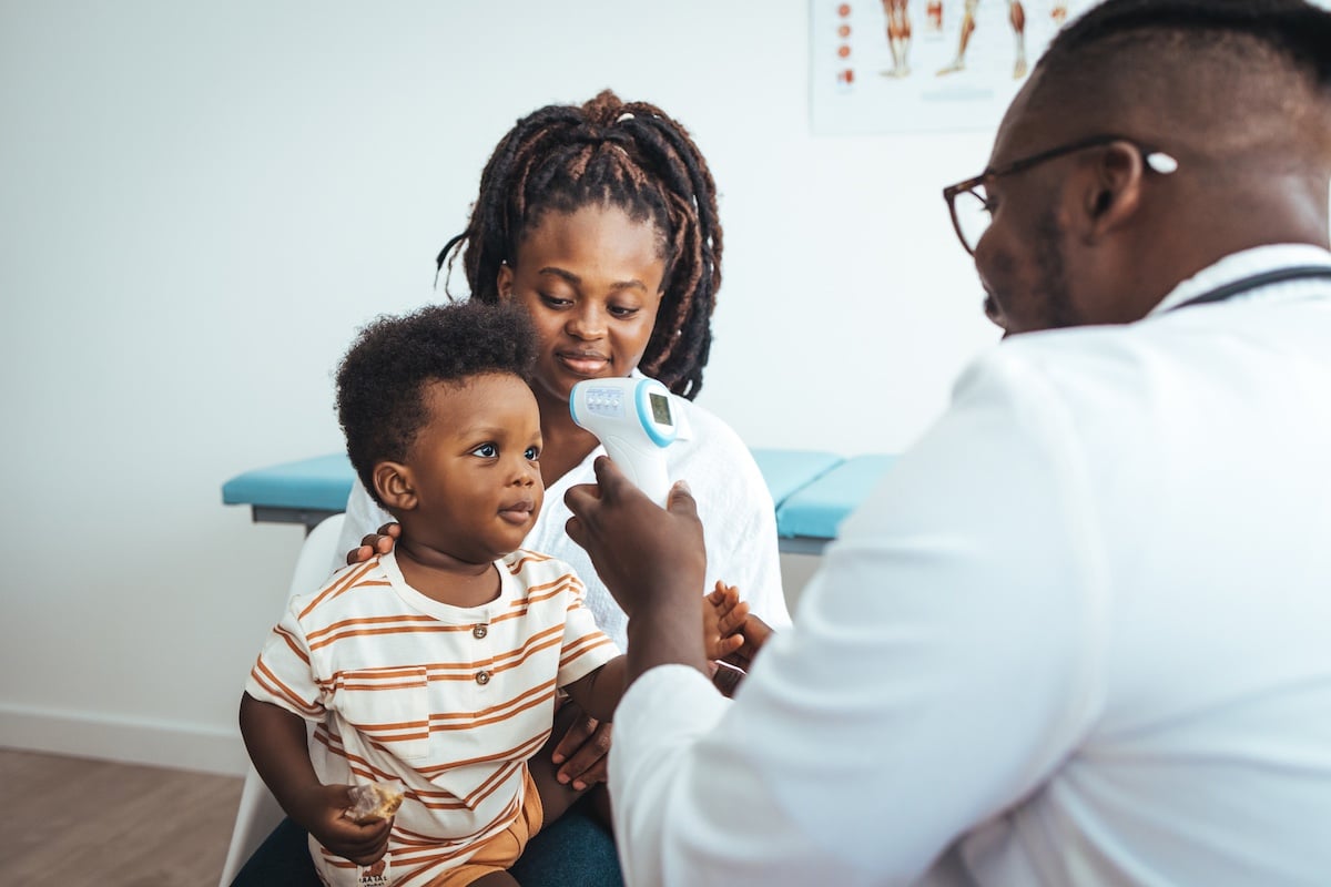 Doctor measuring temperature of boy with infrared thermometer at hospital