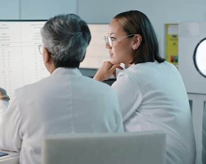 Science, hospital and women on computer for research, medical report and data analytics in laboratory. Healthcare, teamwork and female scientist in discussion for analysis, results and biotechnology