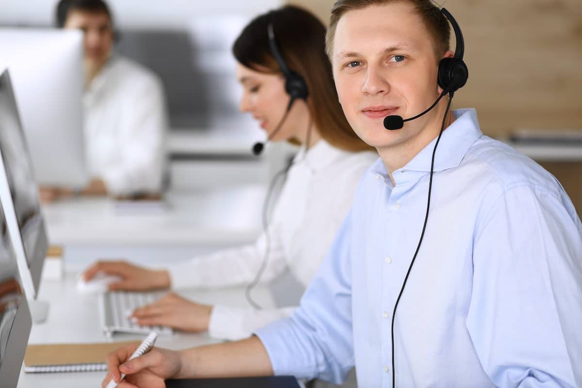 Call center. Group of diverse operators at work. Focus on businessman in headset at customer service office. Business concept