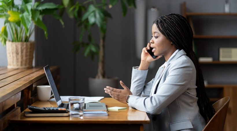 Young woman office worker using mobile phone, making phonecall in workplace