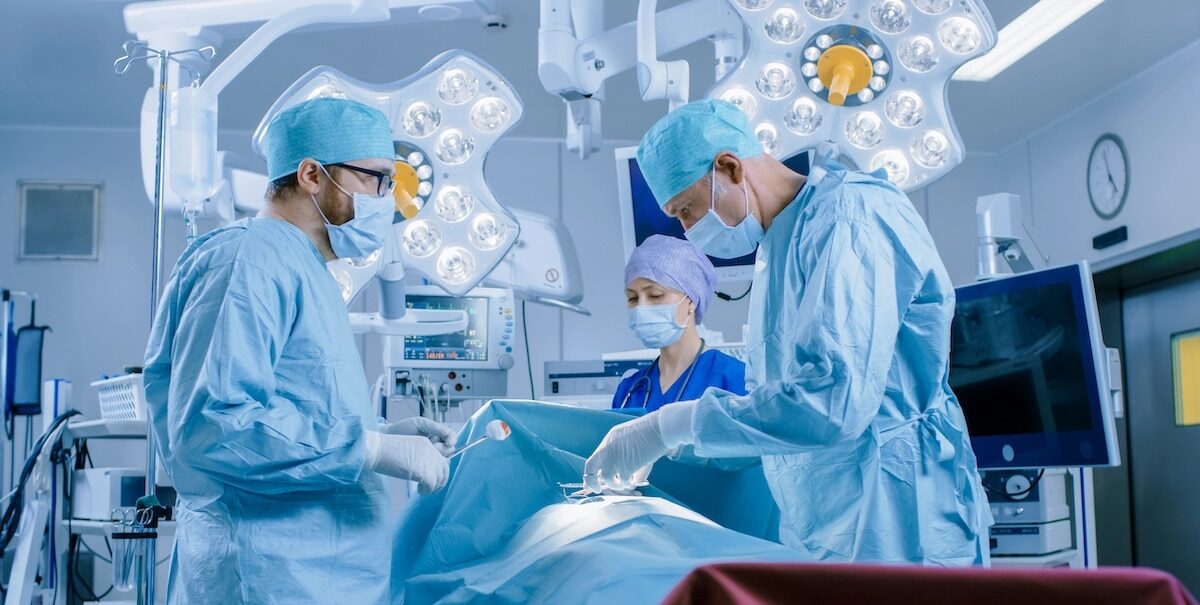 In the Hospital Operating Room Diverse Team of Professional Surgeons and Nurses Suture Wound after Successful Surgery.